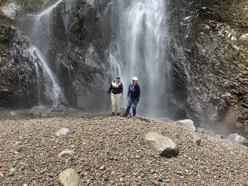 Friends swimming beneath a waterfall near Cahuasquí