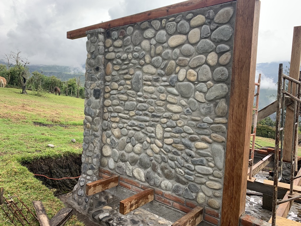 Close view of a finished stone wall panel framed in heavy timber