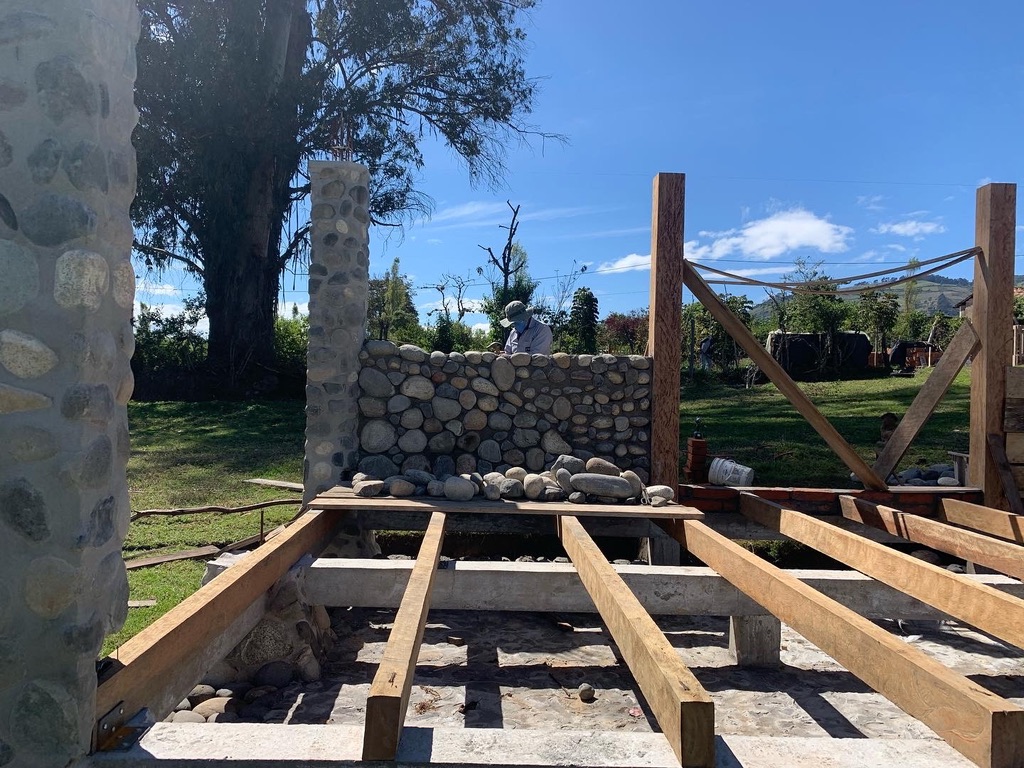 Interior of the studio showing stone columns, wood joists, and a stone wall under construction