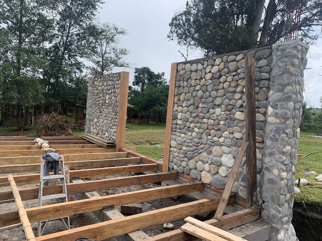 Wooden floor joists laid between finished river-stone walls