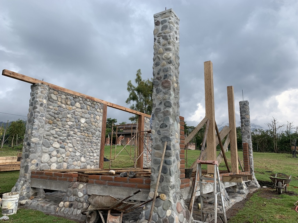 Building site with stone columns and timber supports under a cloudy sky