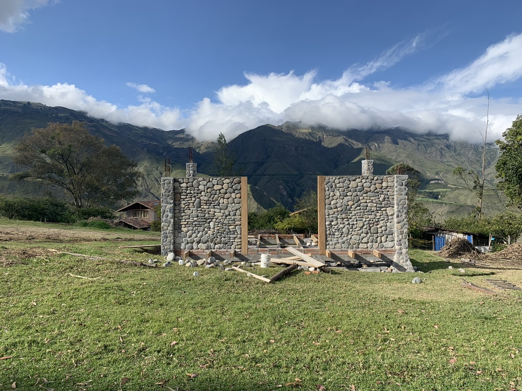 Wide view of the stone studio build framed against the valley and mountain peaks