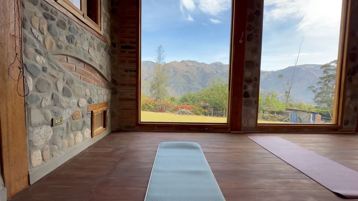 Mats laid on the studio floor facing floor-to-ceiling windows onto the mountains